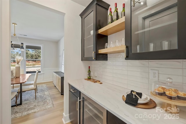 kitchen featuring backsplash, beverage cooler, light stone counters, and light hardwood / wood-style flooring