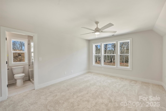 interior space with ceiling fan, light colored carpet, connected bathroom, and vaulted ceiling