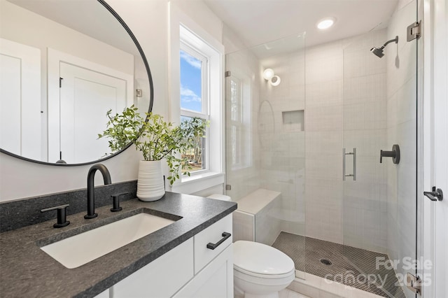 bathroom featuring vanity, a shower with shower door, and toilet