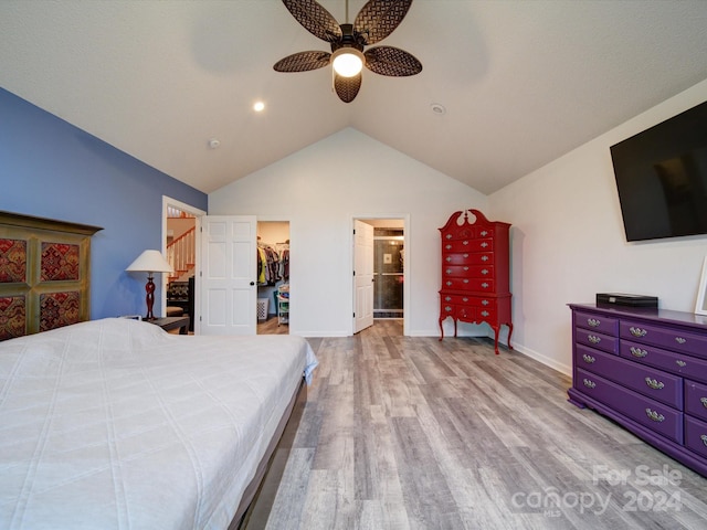 bedroom featuring a closet, light hardwood / wood-style floors, lofted ceiling, a walk in closet, and ceiling fan