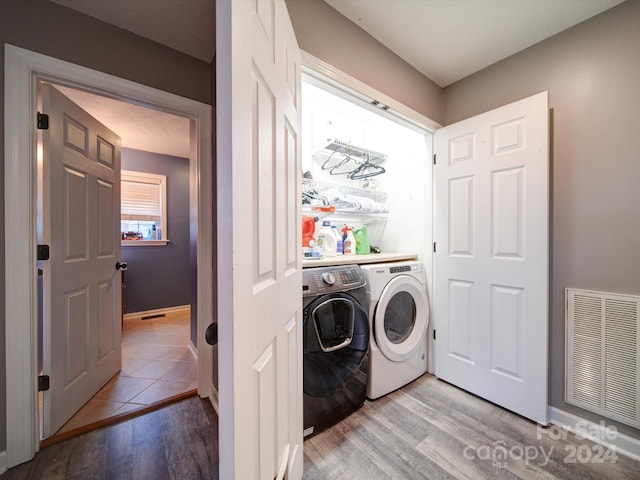 laundry area with washer and clothes dryer and light hardwood / wood-style floors