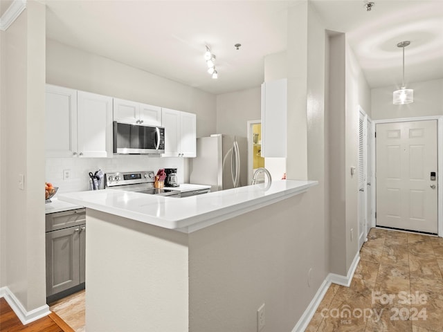 kitchen with tasteful backsplash, white cabinets, kitchen peninsula, hanging light fixtures, and appliances with stainless steel finishes