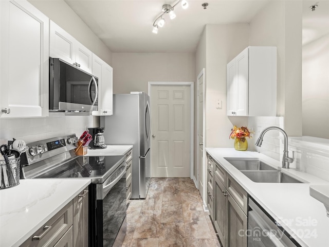 kitchen featuring stainless steel appliances, backsplash, sink, and white cabinetry