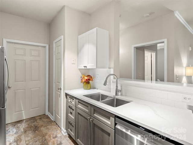 kitchen with appliances with stainless steel finishes, decorative backsplash, light stone counters, white cabinets, and sink