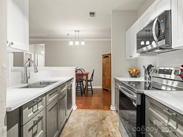 kitchen featuring white cabinets, appliances with stainless steel finishes, sink, and decorative light fixtures