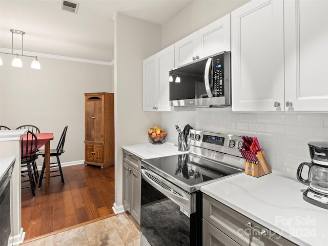 kitchen featuring white cabinets, wood-type flooring, appliances with stainless steel finishes, and decorative light fixtures