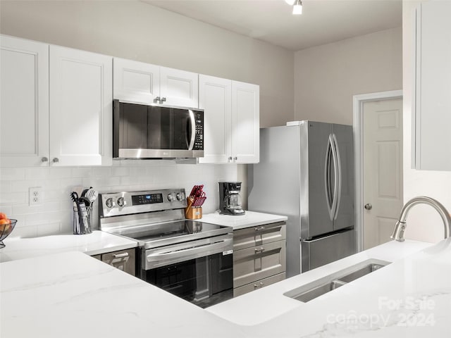 kitchen with tasteful backsplash, sink, stainless steel appliances, and white cabinets