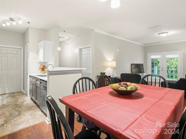 dining area featuring french doors, light hardwood / wood-style floors, crown molding, and sink