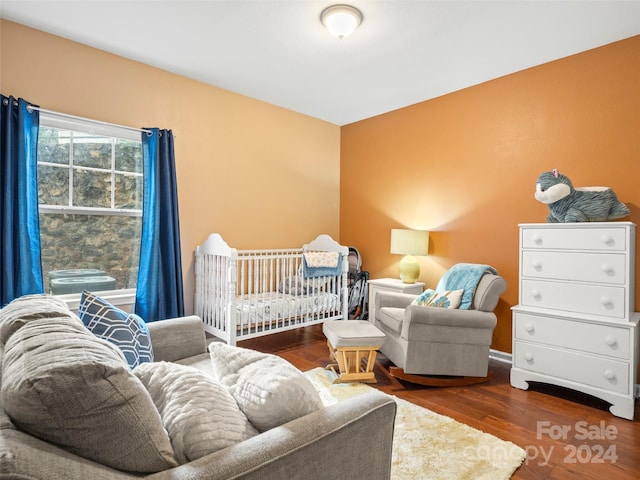 bedroom featuring a nursery area and dark wood-type flooring