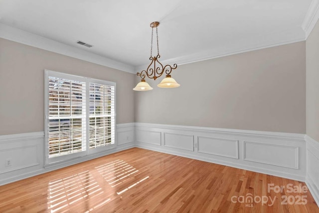 spare room featuring ornamental molding, a chandelier, and light hardwood / wood-style flooring