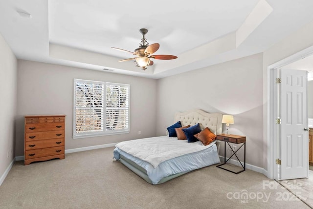 carpeted bedroom with a raised ceiling and ceiling fan