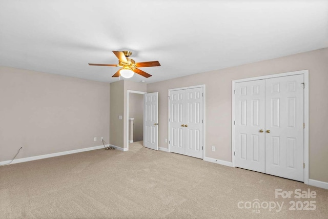 unfurnished bedroom with light carpet, two closets, and ceiling fan