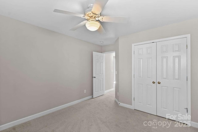 unfurnished bedroom featuring ceiling fan, light colored carpet, and a closet