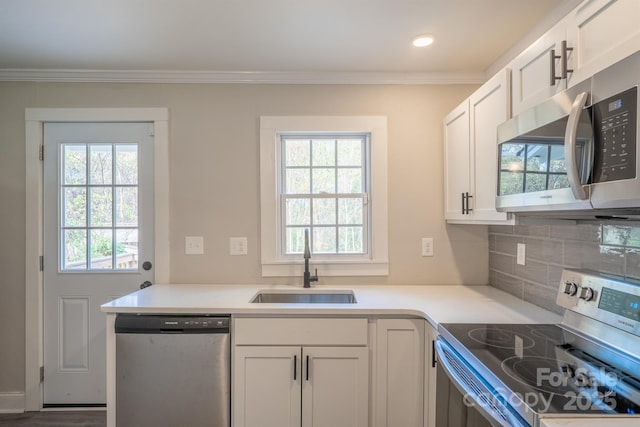 kitchen with tasteful backsplash, sink, white cabinets, stainless steel appliances, and crown molding