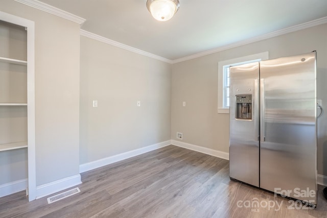 kitchen with stainless steel refrigerator with ice dispenser, ornamental molding, and light wood-type flooring