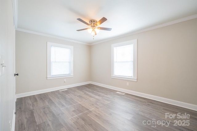 empty room featuring ornamental molding, plenty of natural light, and light wood-type flooring