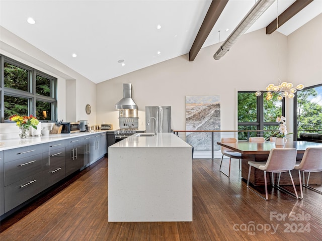 kitchen with a wealth of natural light, a center island with sink, beamed ceiling, and dark hardwood / wood-style floors