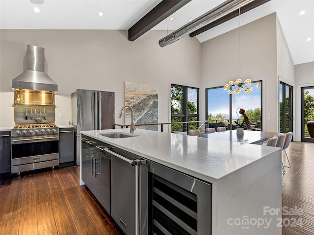 kitchen with beverage cooler, high quality appliances, a center island with sink, sink, and wall chimney range hood