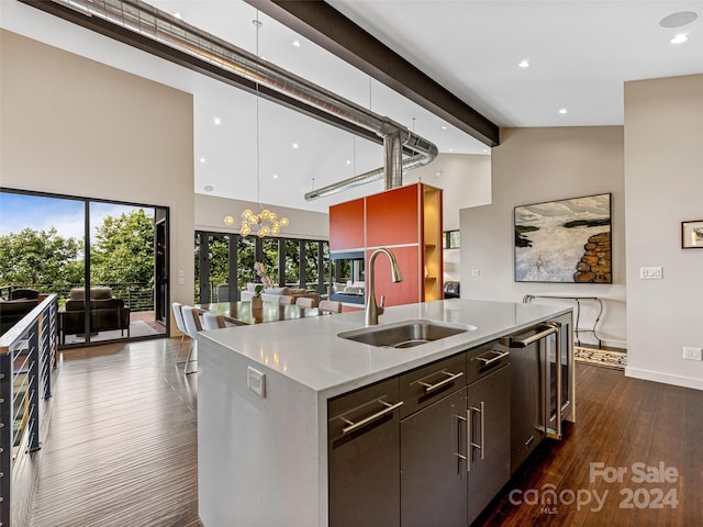 kitchen featuring dark hardwood / wood-style floors, sink, an island with sink, beam ceiling, and dark brown cabinetry