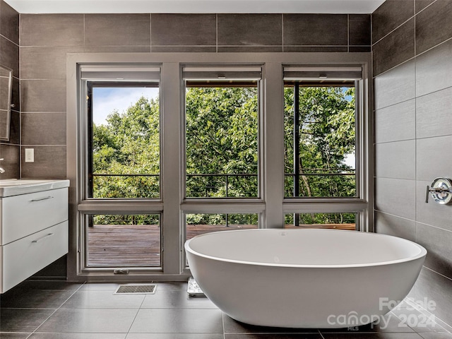 bathroom with vanity, tile walls, a washtub, and tile patterned floors