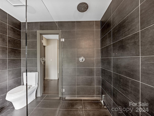 bathroom featuring tiled shower, tile walls, tile patterned flooring, and toilet