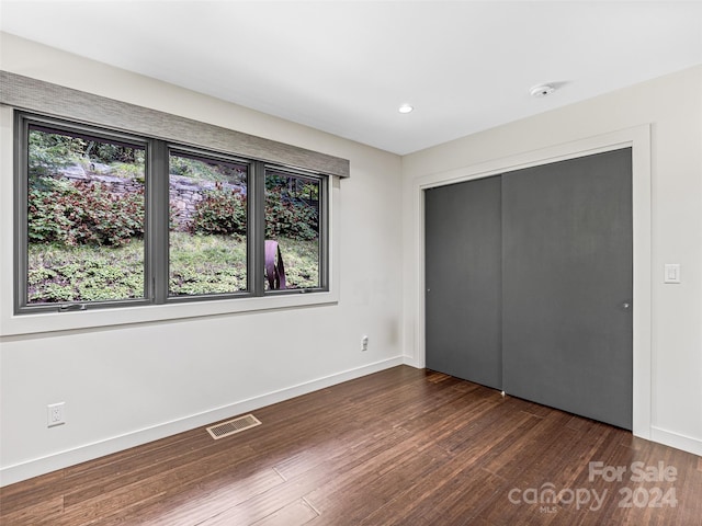 unfurnished bedroom featuring a closet and dark wood-type flooring