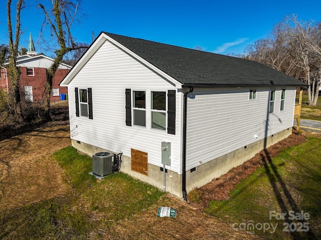 view of side of home with central AC and a lawn