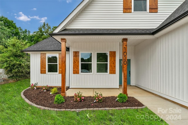 view of exterior entry featuring a yard and covered porch