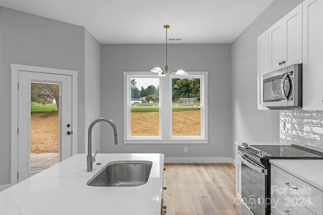 kitchen featuring light stone countertops, appliances with stainless steel finishes, hanging light fixtures, and a healthy amount of sunlight