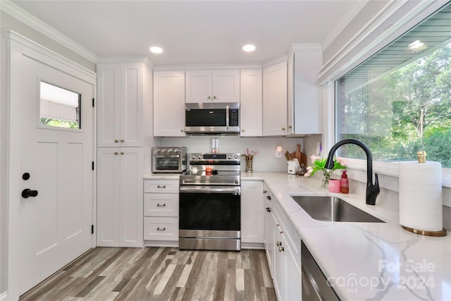 kitchen with white cabinetry, sink, stainless steel appliances, and light stone counters