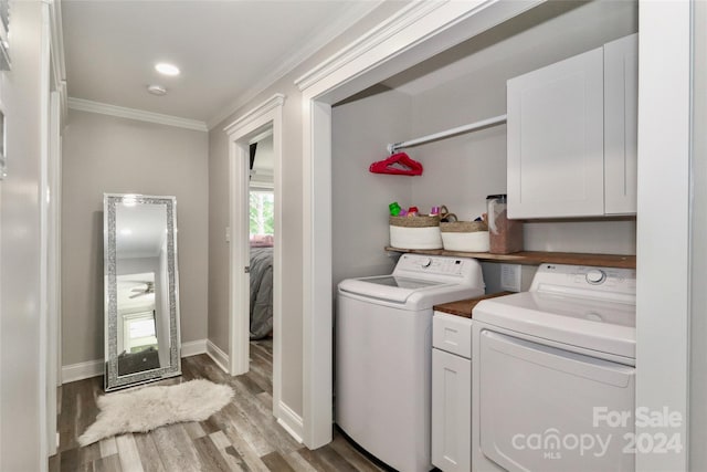 laundry area featuring separate washer and dryer, ornamental molding, hardwood / wood-style floors, and cabinets