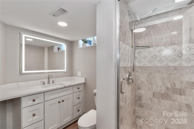 bathroom featuring a tile shower, vanity, and toilet