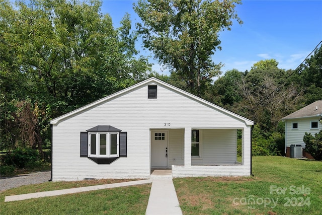 bungalow-style home with cooling unit, a front lawn, and covered porch