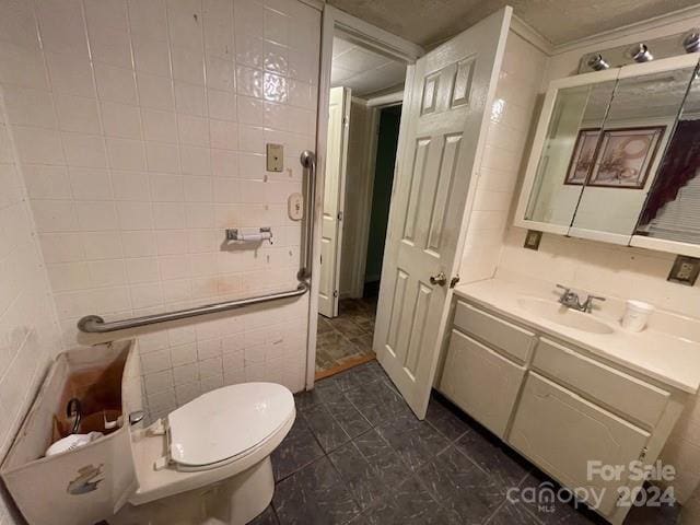 bathroom with tile patterned floors, vanity, toilet, and tile walls