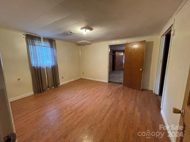 unfurnished room featuring hardwood / wood-style floors and crown molding