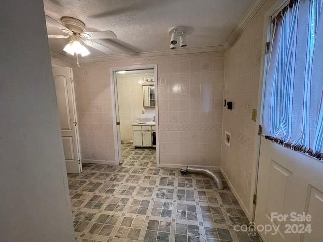 laundry room with ceiling fan, tile walls, and ornamental molding