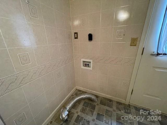 laundry room with tile patterned flooring, tile walls, and hookup for a washing machine