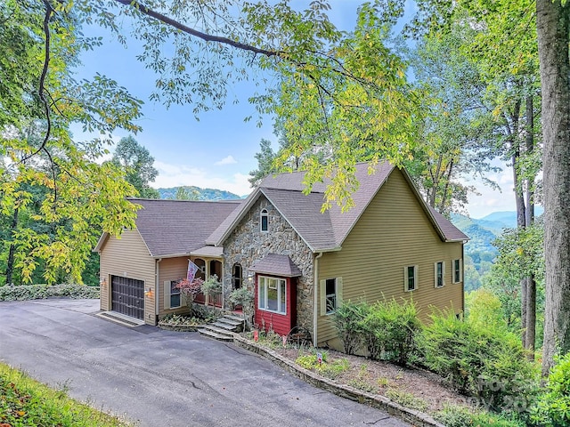 445 Equestrian Dr, Waynesville, NC 28786 - view of front of home with stone siding, a mountain view, a garage, and asphalt driveway