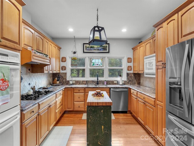 445 Equestrian Dr, Waynesville, NC 28786 - kitchen featuring appliances with stainless steel finishes, a sink, light stone countertops, light wood-style floors, and recessed lighting