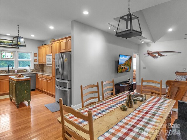 dining area with light wood-type flooring, sink, and lofted ceiling