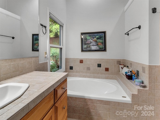 bathroom with a relaxing tiled tub and vanity