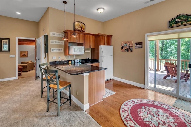 445 Equestrian Dr, Waynesville, NC 28786 - kitchen featuring white appliances, a breakfast bar, brown cabinetry, a peninsula, and baseboards