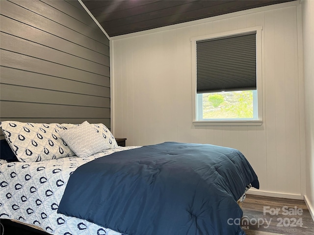 bedroom with lofted ceiling, wood walls, and hardwood / wood-style floors