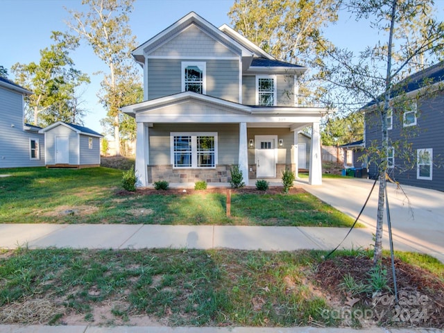 traditional-style home featuring an outdoor structure, a front lawn, and covered porch