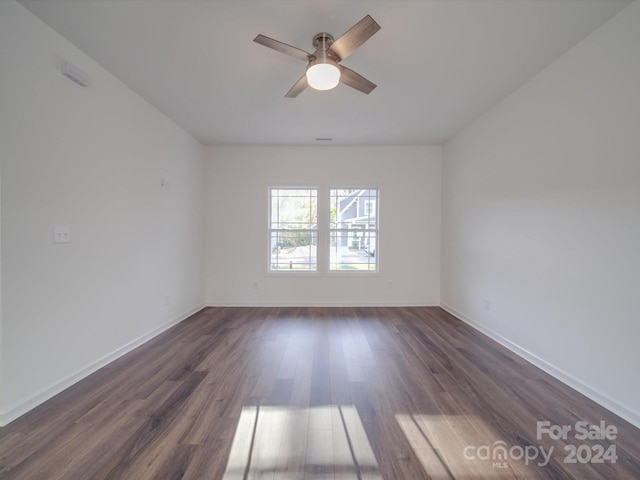 unfurnished room with baseboards, dark wood-style floors, and ceiling fan