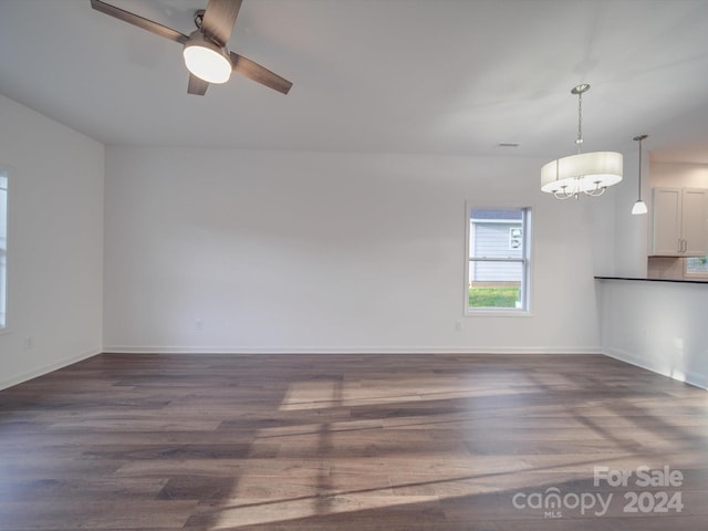 unfurnished living room featuring a ceiling fan, baseboards, and dark wood-style flooring