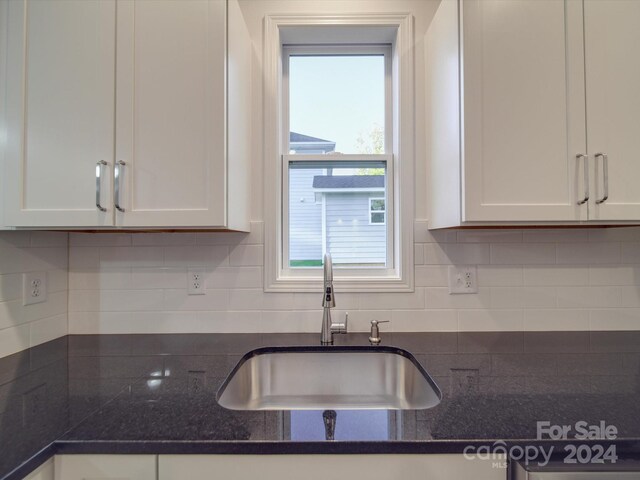 kitchen featuring backsplash, a sink, and white cabinetry