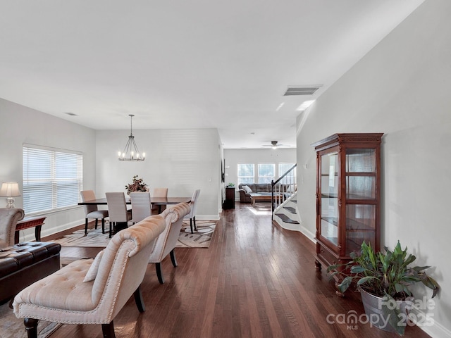 dining space with ceiling fan with notable chandelier and dark hardwood / wood-style flooring