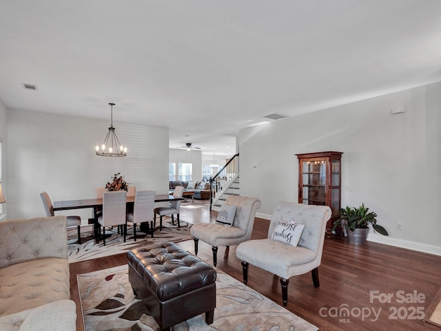 living room with ceiling fan with notable chandelier and hardwood / wood-style floors