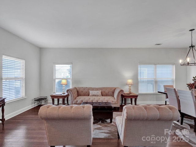 living room with dark hardwood / wood-style flooring and an inviting chandelier